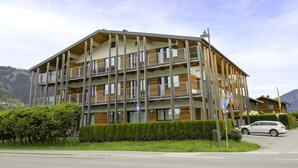 A multi-story building with balconies, a sign indicating a nearby location, and a car parked in front. - Justine (Top 9) by Interhome (Kaprun)
