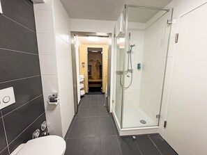 Moderni kylpyhuone, jossa on lasinen suihkuseinä, wc ja pesuallas.