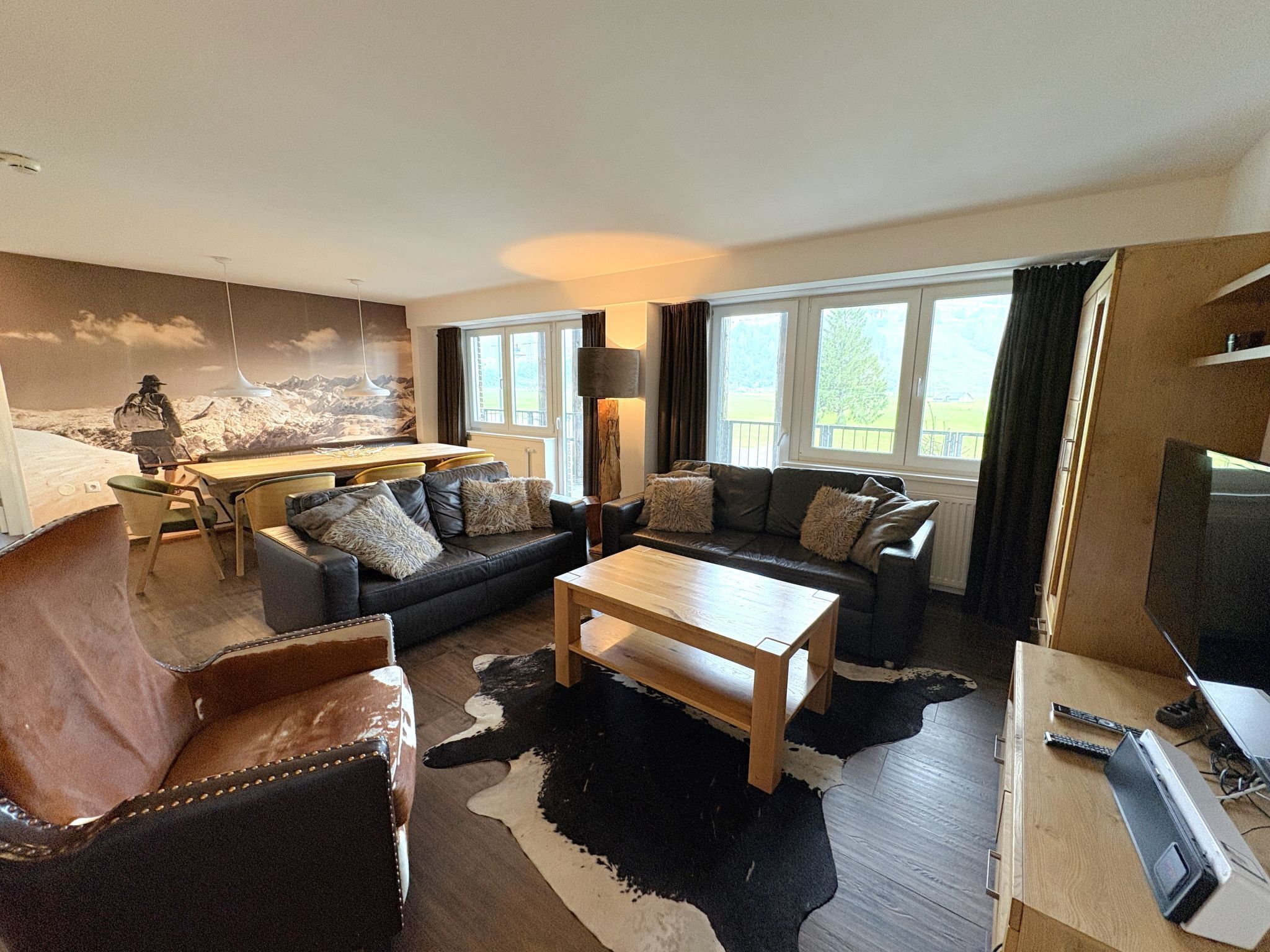 A modern living room with a sofa, armchair, coffee table, and a TV.
