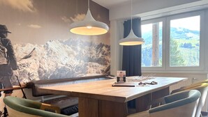 A dining area with a wooden table, two pendant lights, and a bench. - Oskar (Top 4) by Interhome (Kaprun)