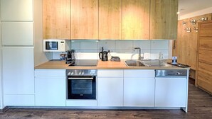 A modern kitchen with wooden cabinets, a built-in oven, a microwave, and a dishwasher. - Oskar (Top 4) by Interhome (Kaprun)