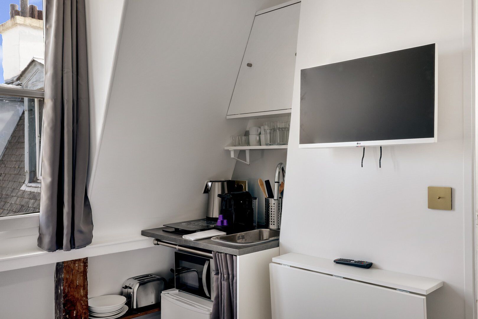 A compact kitchenette with a coffee maker, toaster, and small refrigerator.
