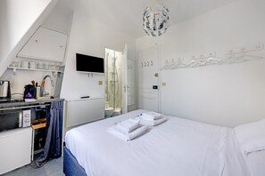 A hotel room with a bed, a desk with a computer, a shower, and a TV. - Paris Marais Rosiers 1 (Paris)