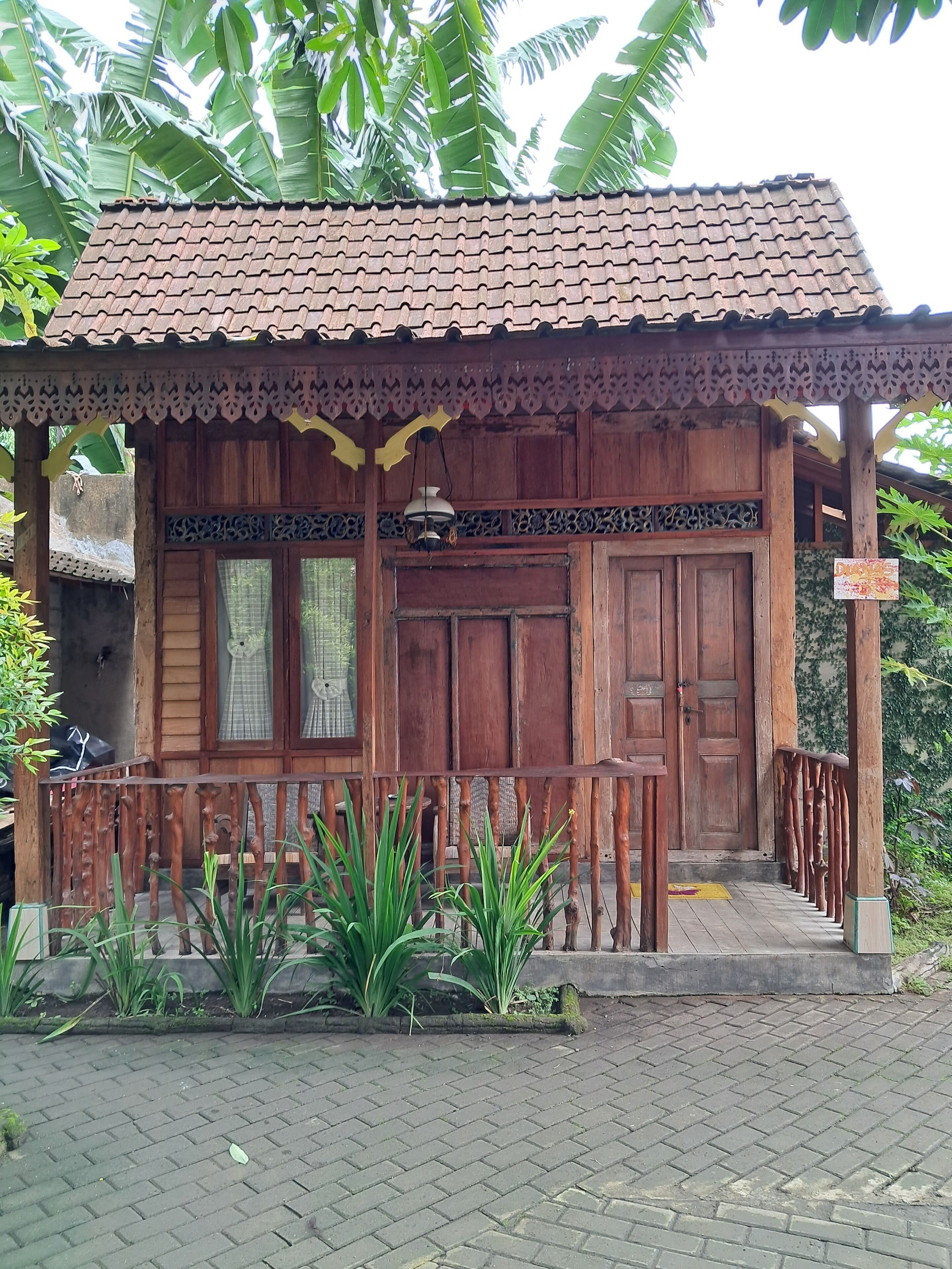 A wooden structure with a tiled roof, a wooden door, and a small porch with a railing.