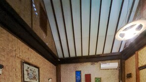 A room with a wooden bed, a bench, a wall-mounted air conditioner, and a framed picture. - Diana's Homestay (Banyuwangi)