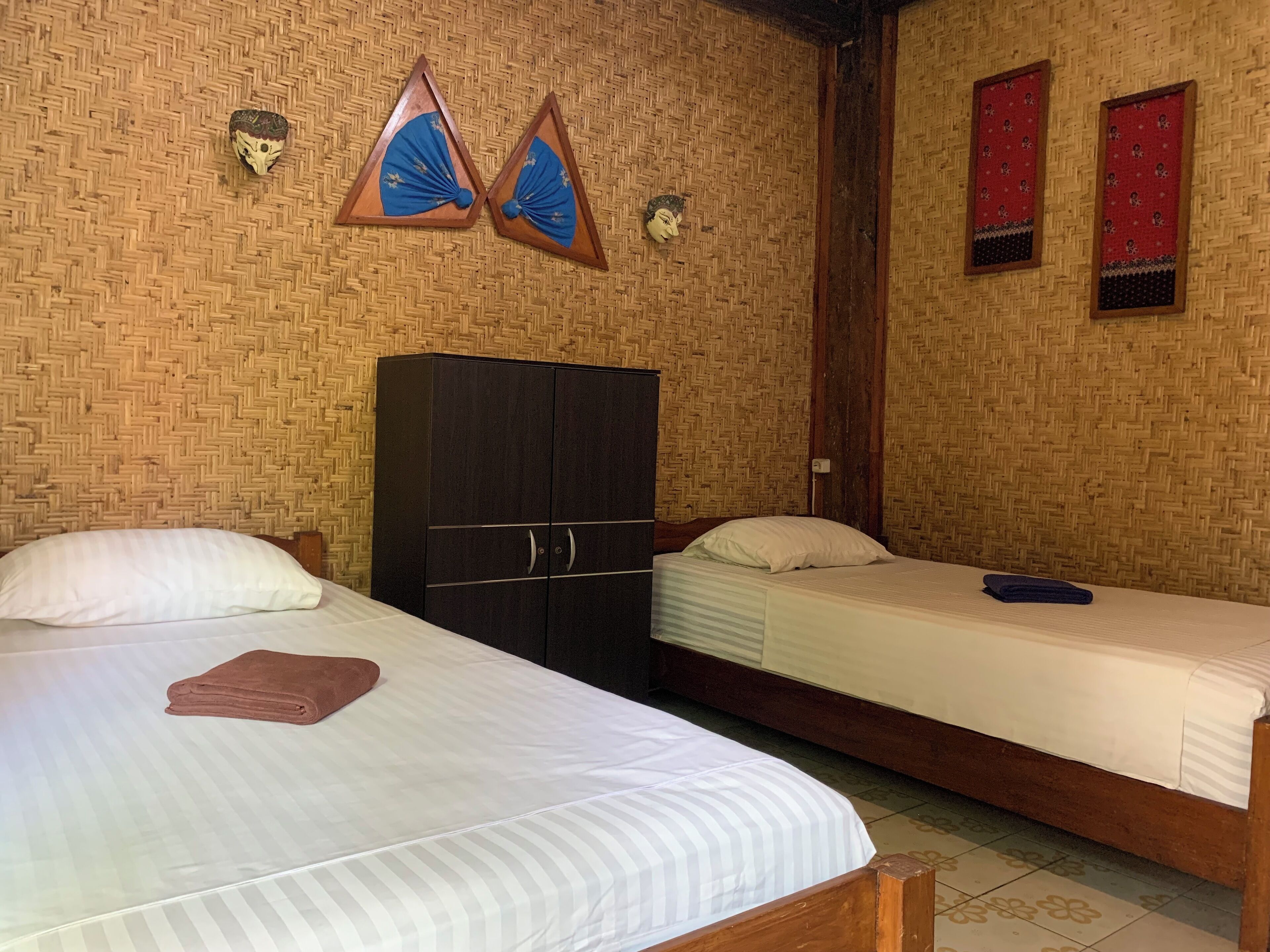 A room with two beds, a wardrobe, and decorative wall panels.
