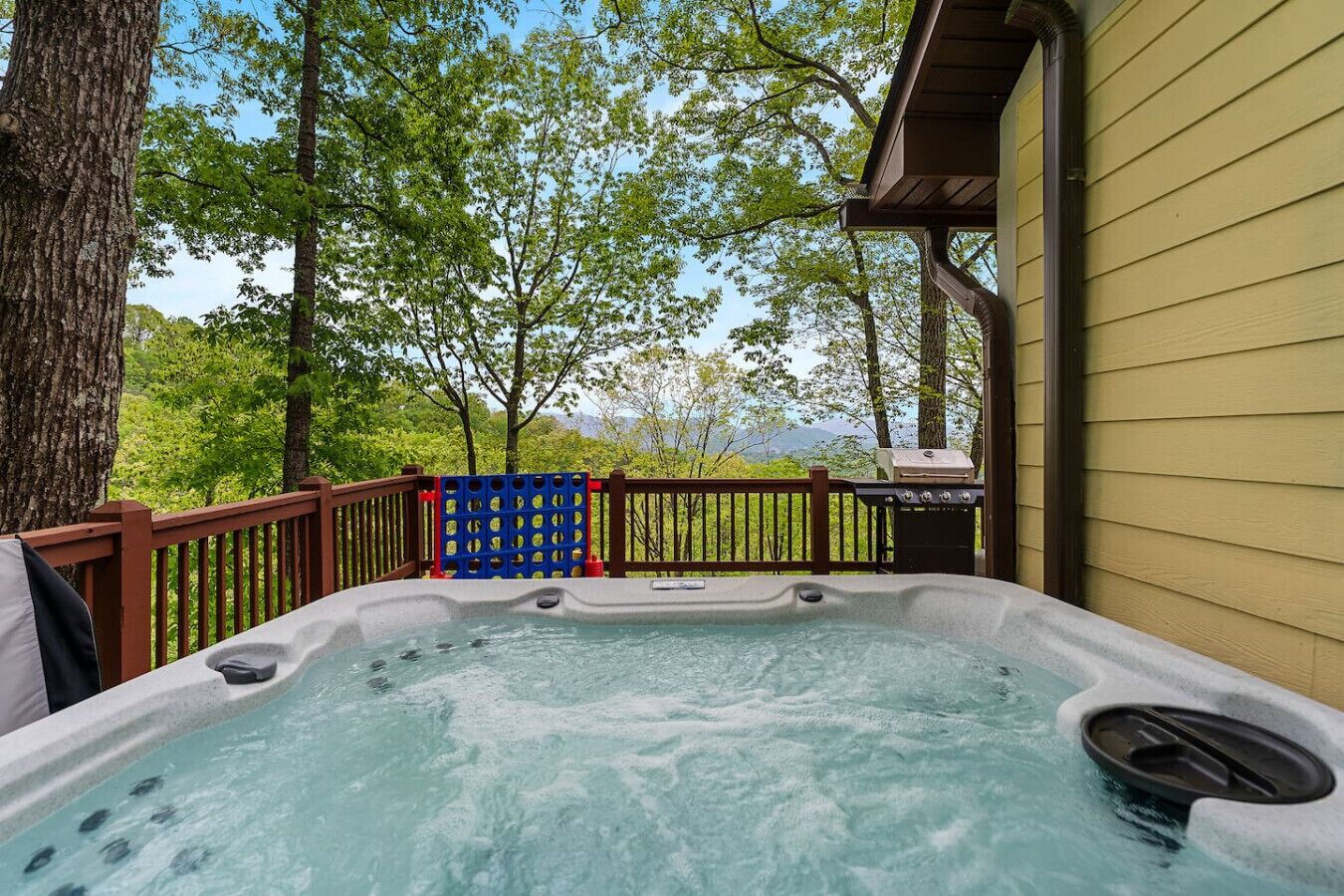 A hot tub on a deck with a view of trees and mountains.