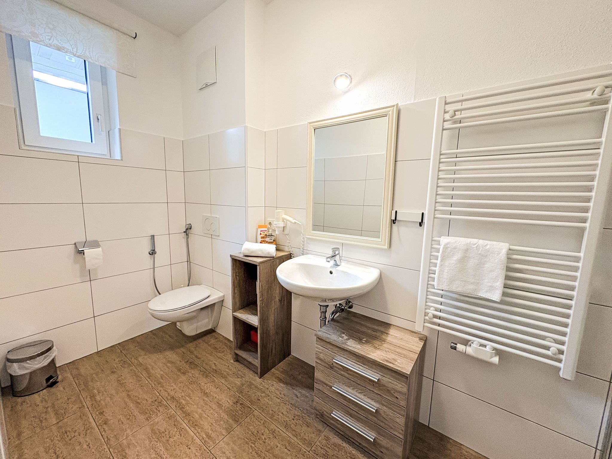 Une salle de bain moderne équipée de toilettes, d’un lavabo et d’un porte-serviettes.