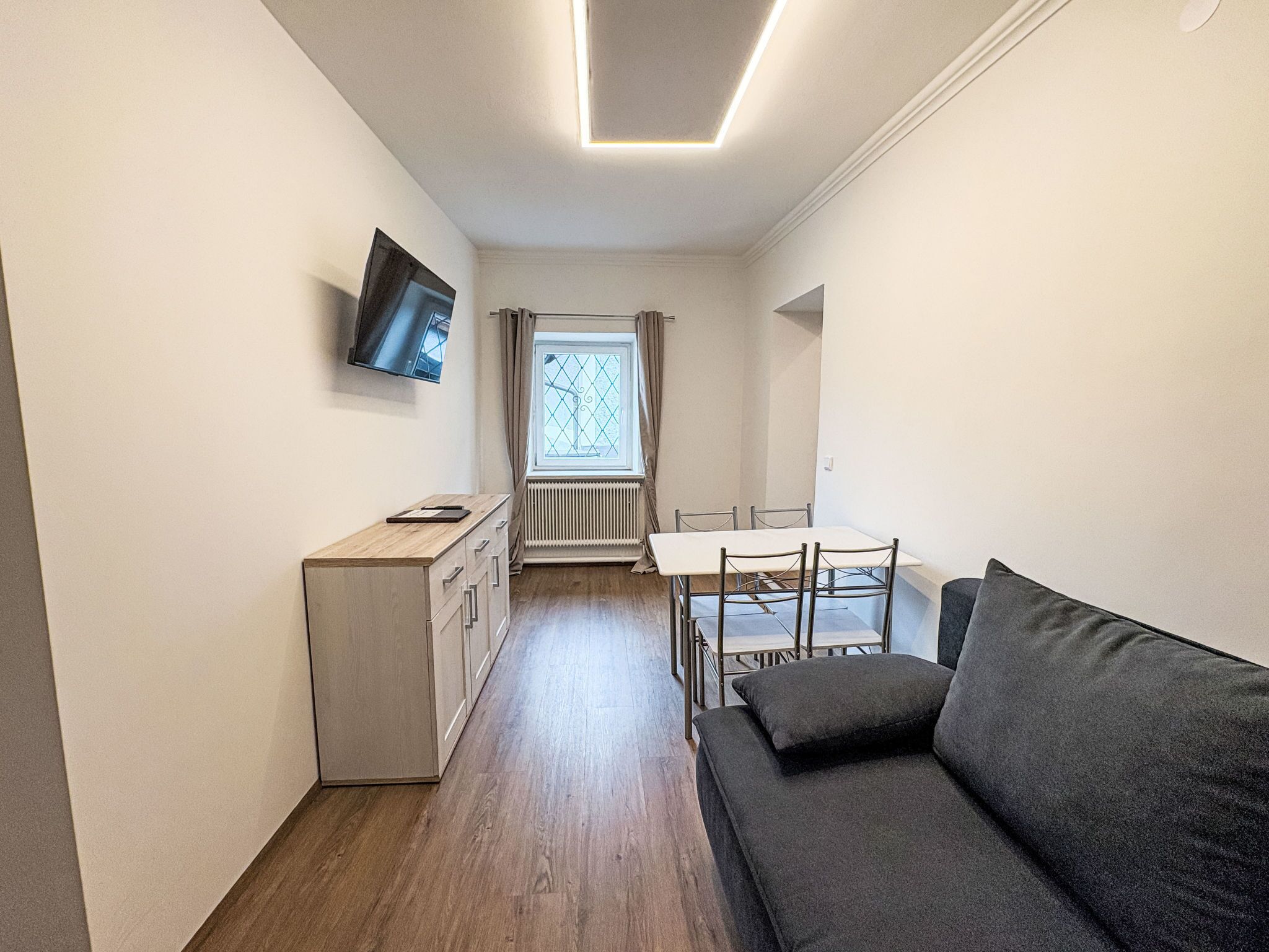 A compact living space with a kitchenette, a dining table, and a sofa.