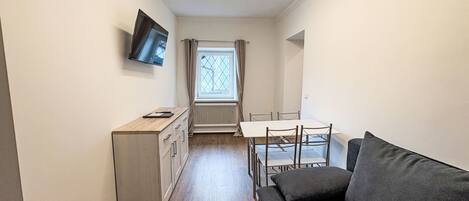A compact living space with a kitchenette, a dining table, and a sofa.
