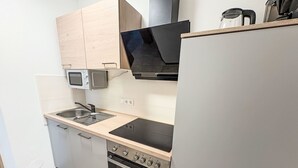 Eine kompakte Küche mit Mikrowelle, Herd, Backofen und einer schwarzen Dunstabzugshaube.