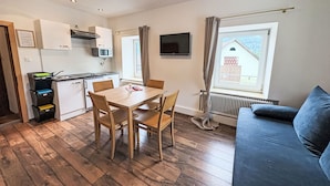 Un espacio habitable compacto con kitchenette, comedor y sofá.