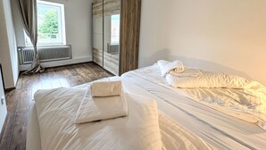 Un dormitorio con dos camas, un radiador, una ventana con cortinas y un armario.