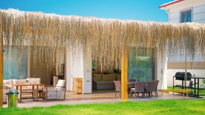 An outdoor seating area with a thatched roof, a sofa set, and a dining table. - Jessica villas 2 (Hisarönü)
