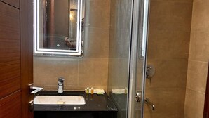 Ein modernes Badezimmer mit Glasdusche, einem Waschtisch und einem beleuchteten Spiegel.