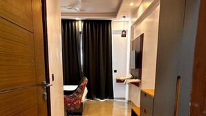 Ein Hotelzimmer mit Holztür, einem Bett, einem Fernseher, einem Schreibtisch und einem Stuhl.