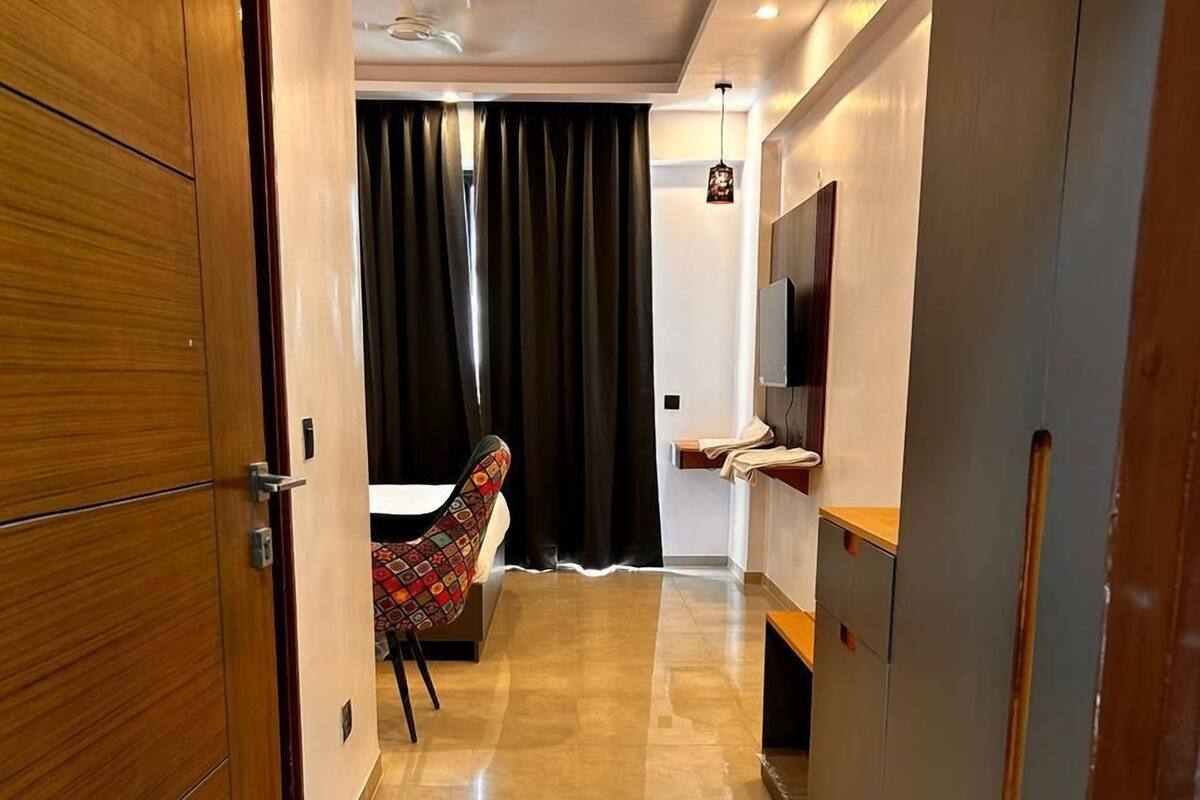 Habitación de hotel con puerta de madera, una cama, un televisor, un escritorio y una silla.