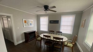 Une salle à manger avec une table ronde et six chaises, un ventilateur de plafond et une cheminée.