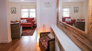 A living room with a red sofa, a wicker chair, a wooden bench, and a large mirror. - THE BURMA, pet friendly in Letterkenny, County Donegal (Letterkenny)