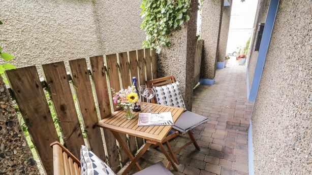 An outdoor patio with a wooden table and chairs, a vase with flowers, and a brick pathway. - THE BURMA, pet friendly in Letterkenny, County Donegal (Letterkenny)