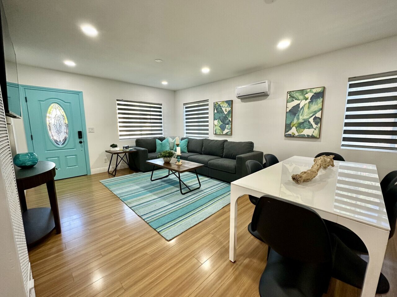 A modern living room with a sofa, coffee table, and a dining area with a table and chairs.