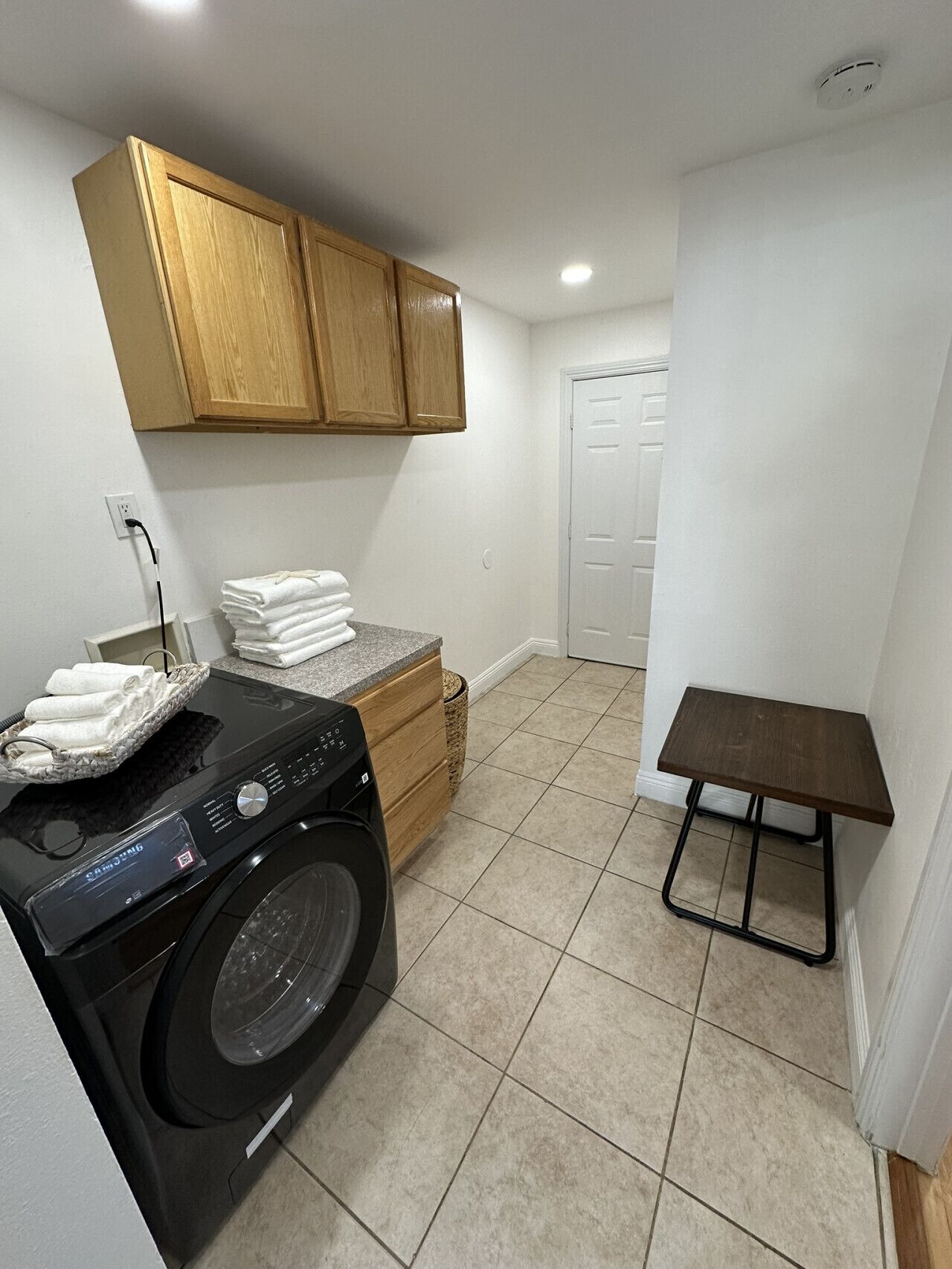 A laundry area with a washing machine, a small table, and a cabinet.