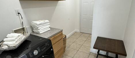 A laundry area with a washing machine, a small table, and a cabinet.