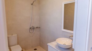 A small, clean bathroom with a toilet, a shower, and a sink.