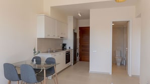 A compact kitchen with a dining area, a washing machine, and a visible bathroom.