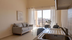 A compact living space with a sofa, a dining table, and a kitchen area with a sink.