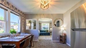 A dining area with a table set for four, a sofa in the background, and a refrigerator to the right. - Lake Views | King Bed | Fenced (Alpena)