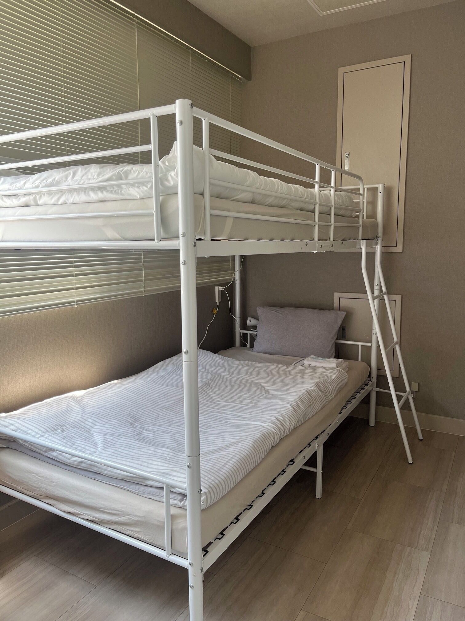 A bunk bed with a ladder, a bedside table, and a wall-mounted mirror.