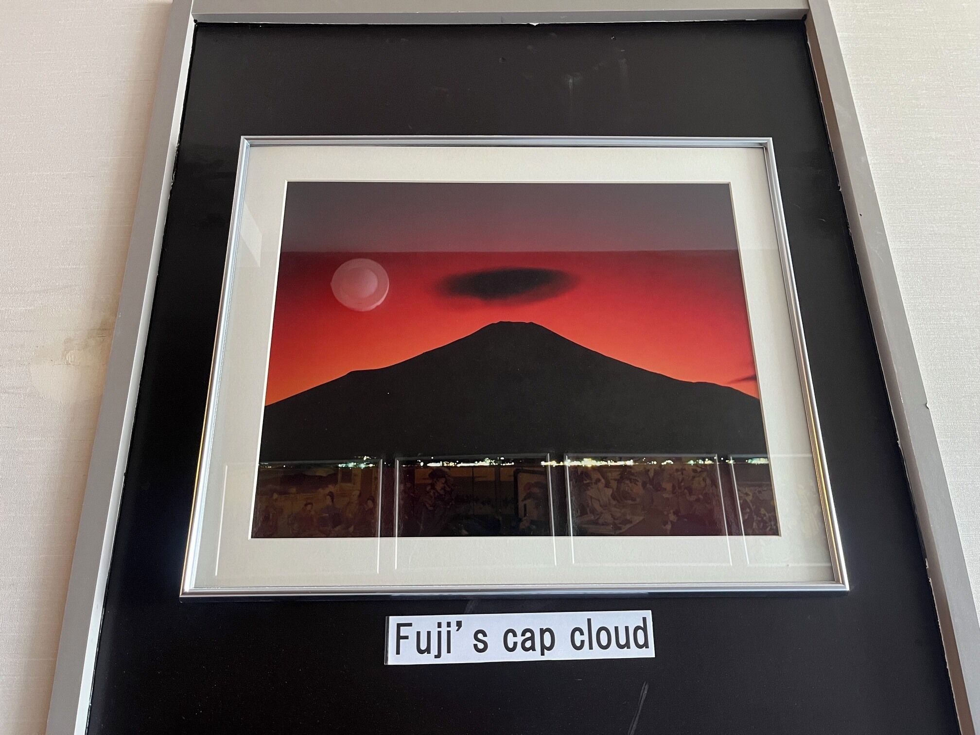 A framed artwork titled 'Fuji's cap cloud' depicting a mountain with a red sky and a moon.