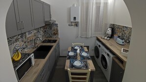 Uma cozinha compacta equipada com micro-ondas, fogão, pia e máquina de lavar.