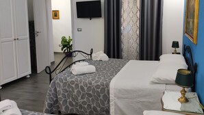 Quarto de hotel com duas camas, televisão, pintura e planta em vaso.