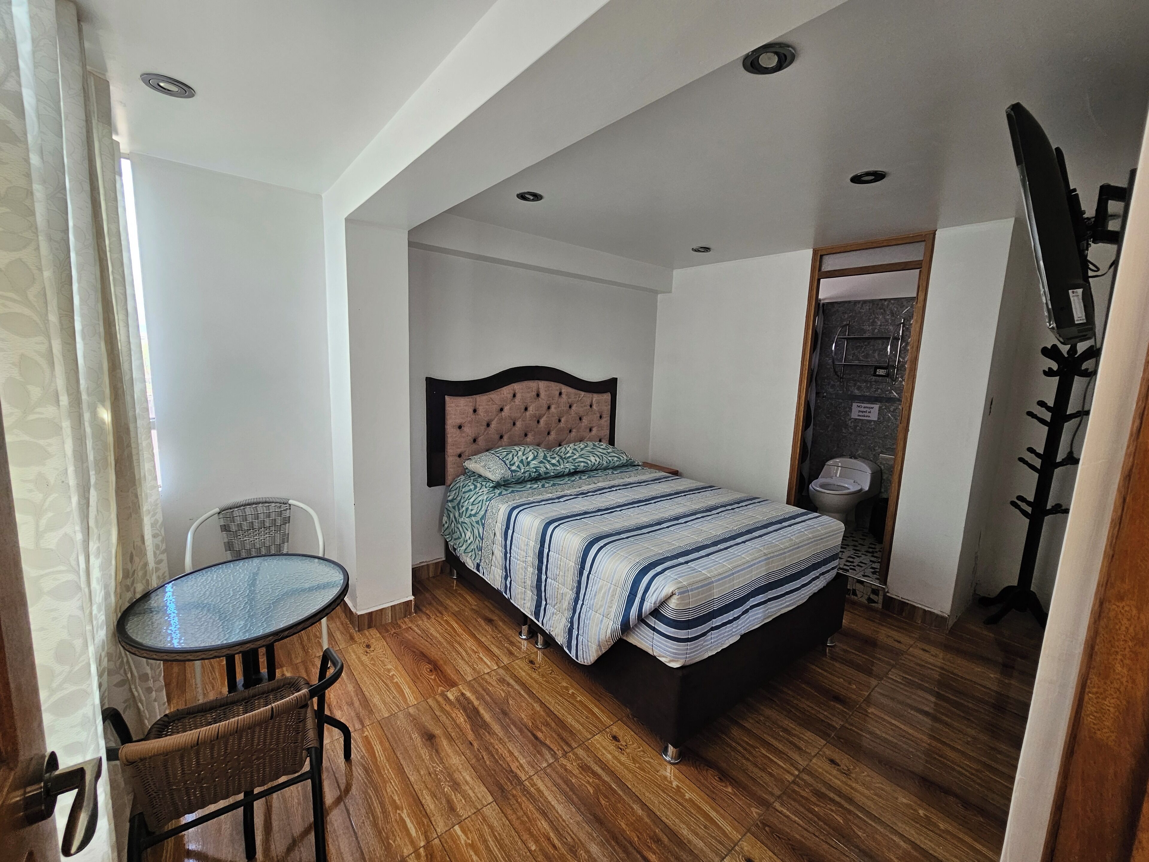 Un dormitorio con una cama, una mesita y una silla.