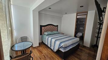 Un dormitorio con una cama, una mesita y una silla.
