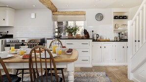 Una cocina moderna con armarios blancos, una mesa de comedor de madera y una disposición para desayunar.