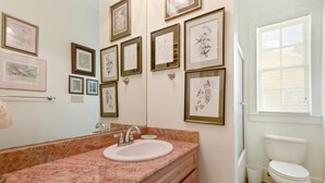Un baño con lavamanos de mármol, una obra de arte enmarcada en la pared y un inodoro.