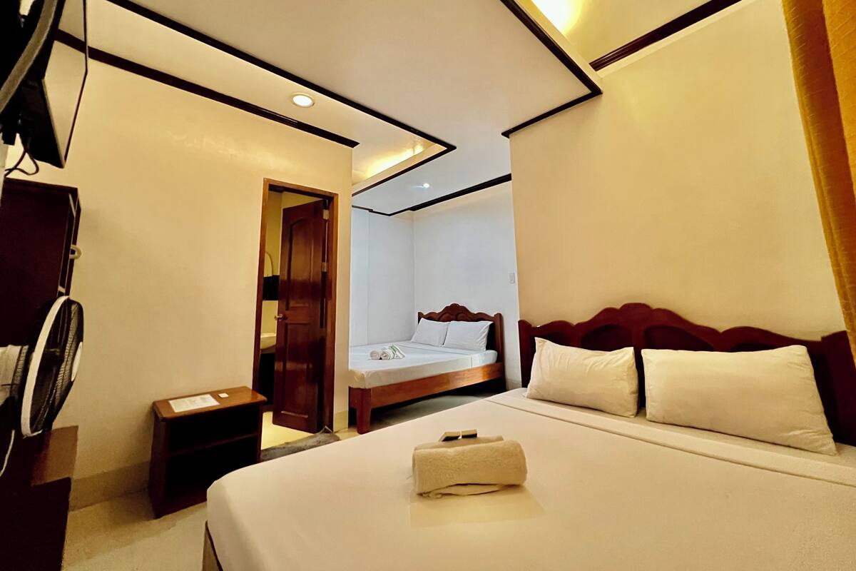 Quarto de hotel com cama, mesa de cabeceira, porta e luz no teto.