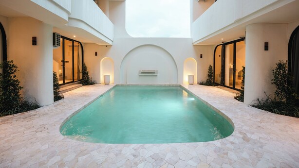 A modern indoor pool with a geometric design, surrounded by white walls and a tiled floor. - NOVO CANGGU (Pererenan)