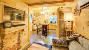 Un intérieur chaleureux, avec des murs en bois, comprenant une cuisine, un coin repas et un salon.