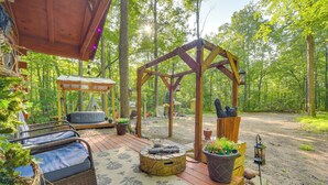 Une terrasse en bois avec des meubles d’extérieur, un foyer en pierre et une pergola agrémentée de lanternes.