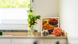 A kitchen counter with a vase of green leaves and yellow flowers, a spice jar, and a framed picture of spices. - GuestReady - Exquisite stay with sea views (Calheta)