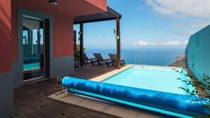 A rooftop pool with a clear view of the ocean, a covered seating area with chairs, and a glass door entrance. - GuestReady - Exquisite stay with sea views (Calheta)