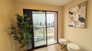A balcony with a city view, a potted plant, and two white chairs. - Excellent location and comfort Rest in Absolute Darkness (Lima)
