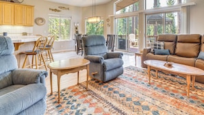 A spacious living room with a large window, a fireplace, and a dining area with wooden chairs and a table. - Golf & Mountain Views - Retreat in Clio (Clio)