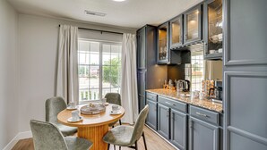 Una cocina moderna con armarios grises, encimera de granito y comedor con una mesa redonda y sillas grises.