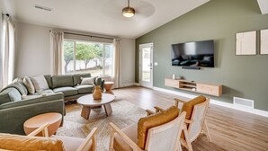 Un salón amplio con un sofá grande, una mesa de centro y un televisor en la pared.