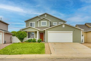 A two-story house with a front garage, a well-maintained lawn, and a small tree in the front yard.